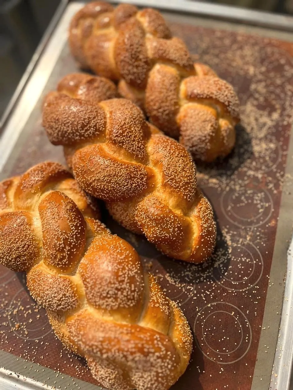 Braided sesame breads on a baking tray