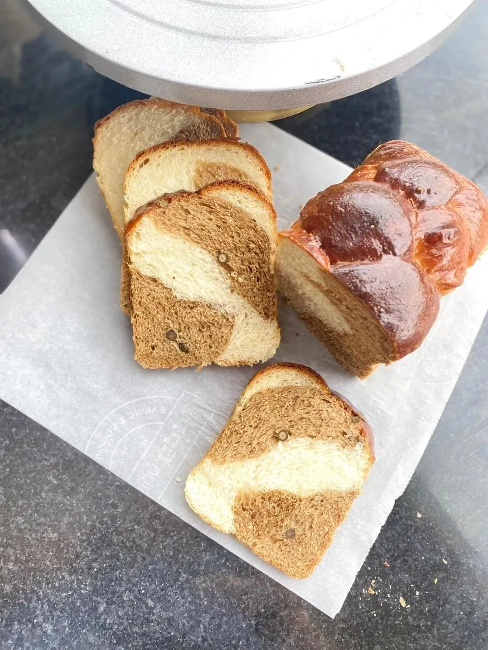 Sliced marble brioche loaf next to a glazed braided bread