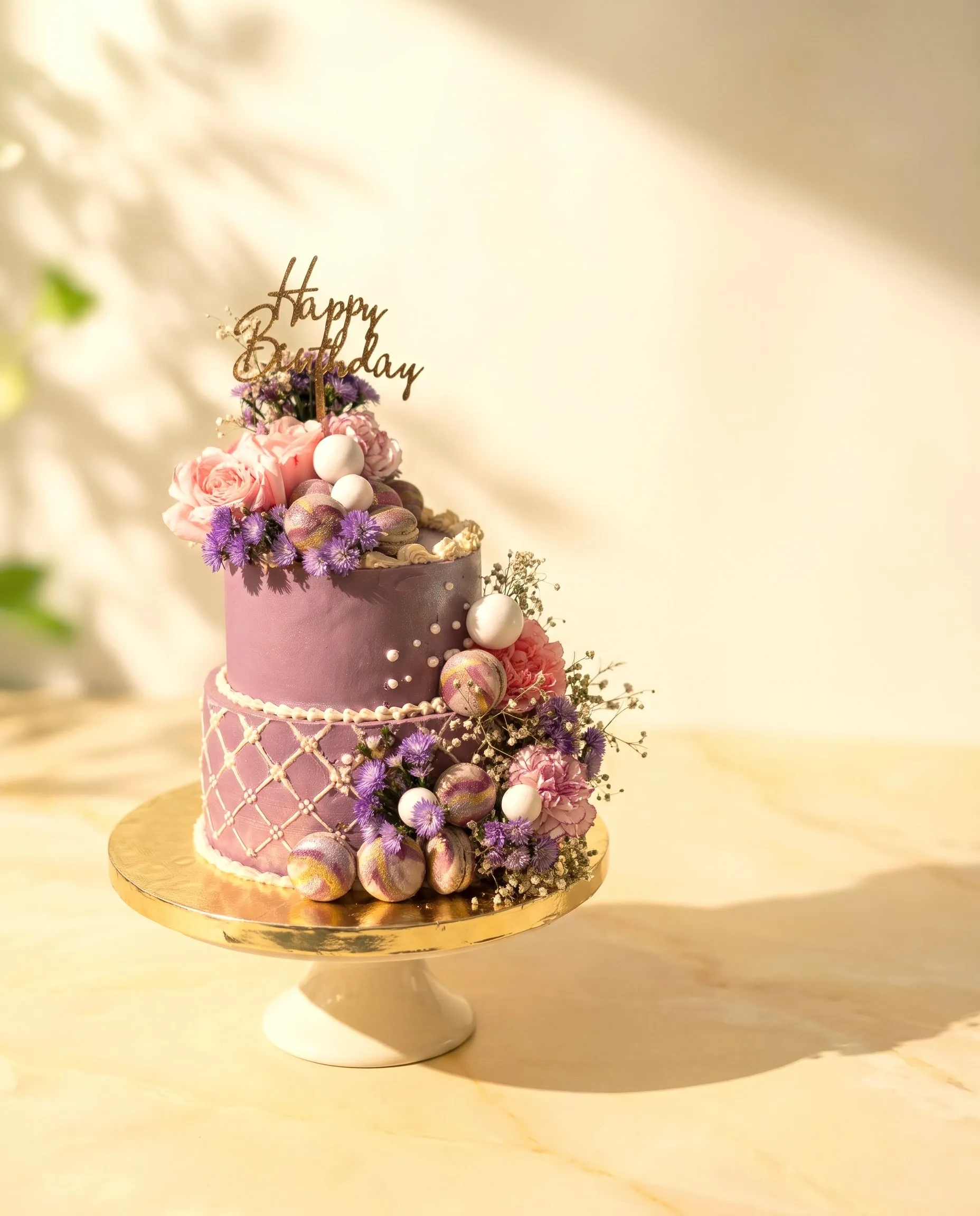 Two-tier purple celebration cake with fresh flowers