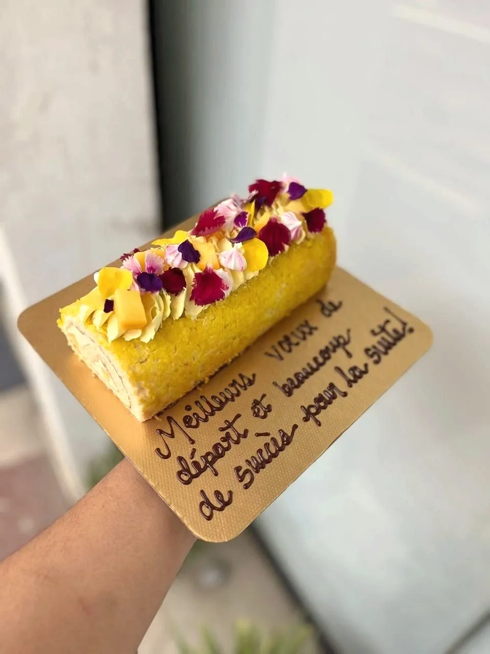 Yellow roll cake with edible flowers and a message card