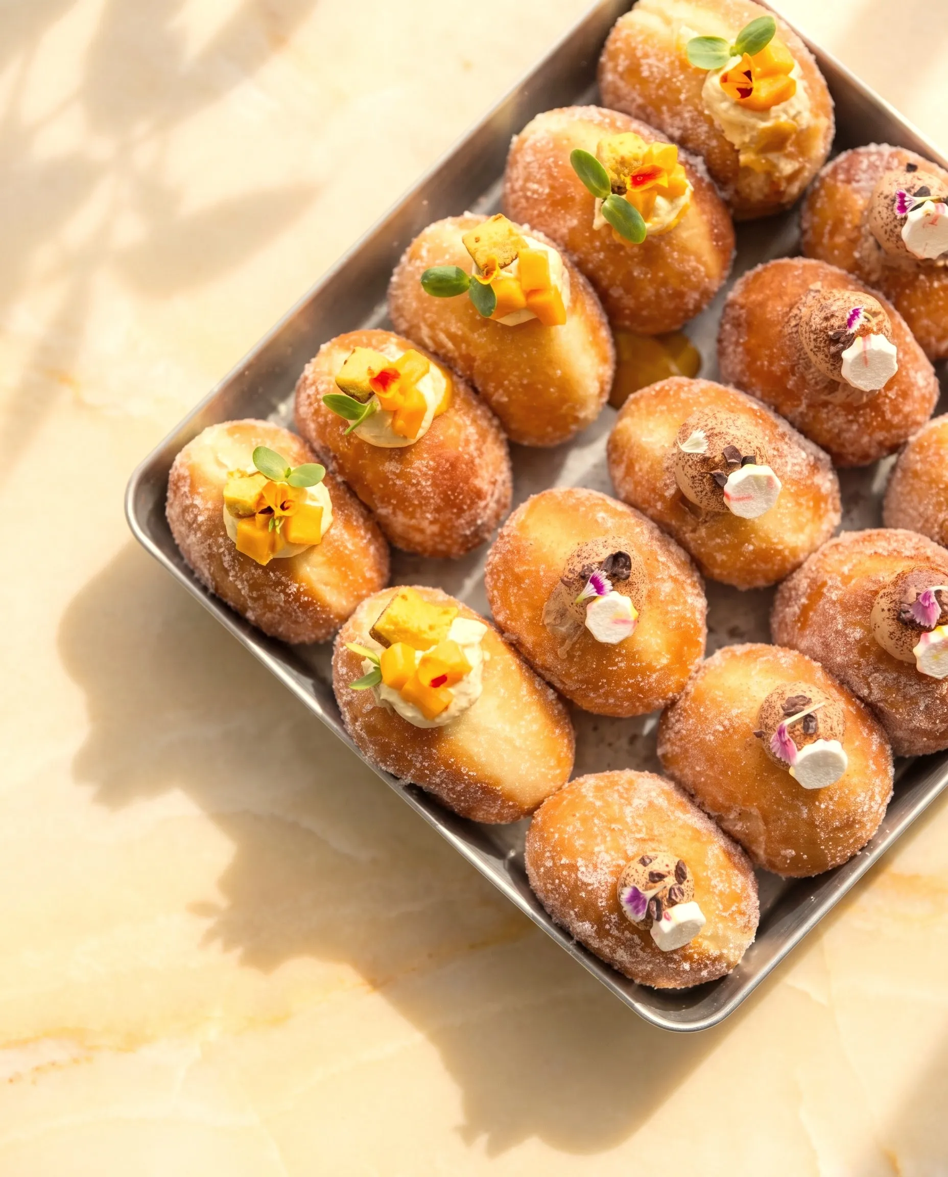 Sugared bomboloni topped with fruit and flowers