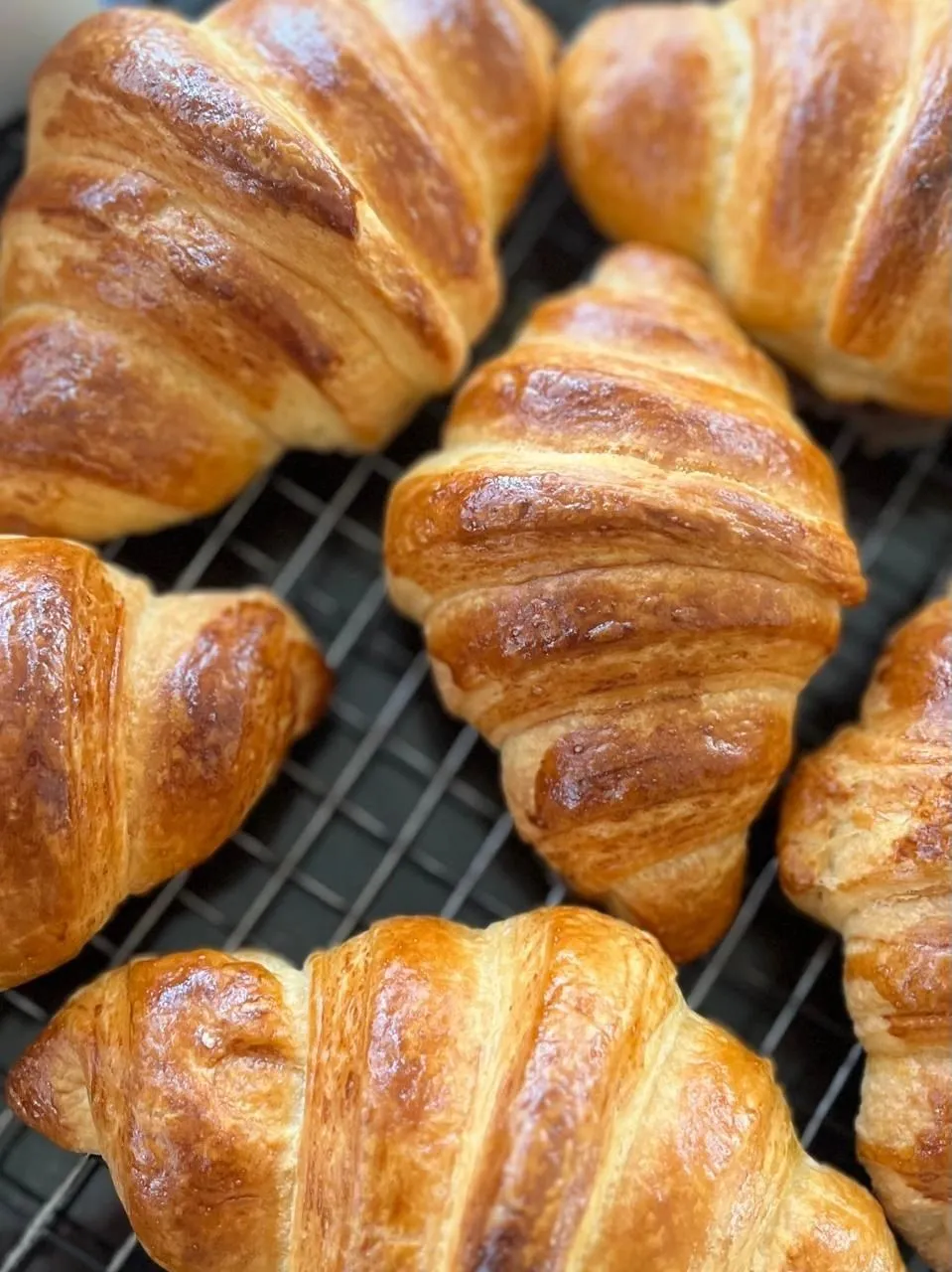 Golden croissants cooling on a wire rack